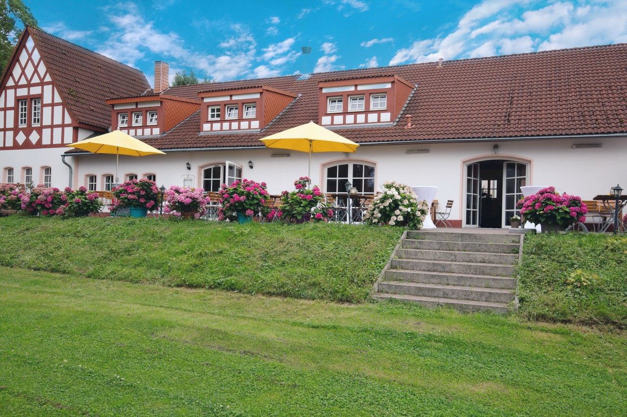 Fachwerk-Hofanlage des Weilerhofs in Hürth mit blühenden Hortensien und blauem Himmel